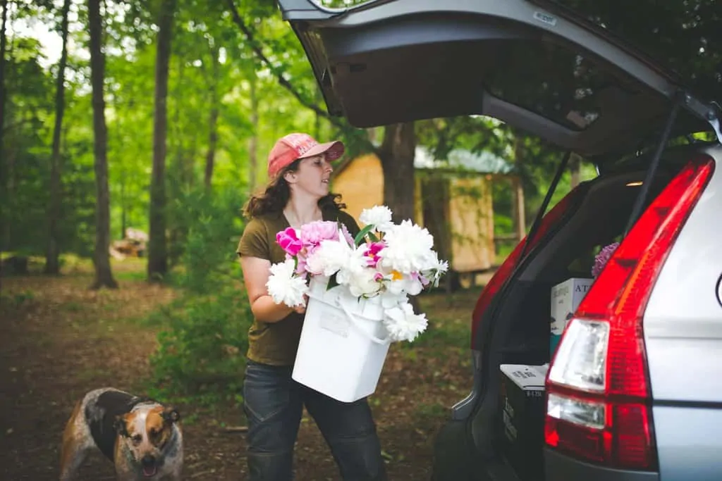 FarmHer Sarah Turkus loading a bucket of pick your own flowers into the back of a car.