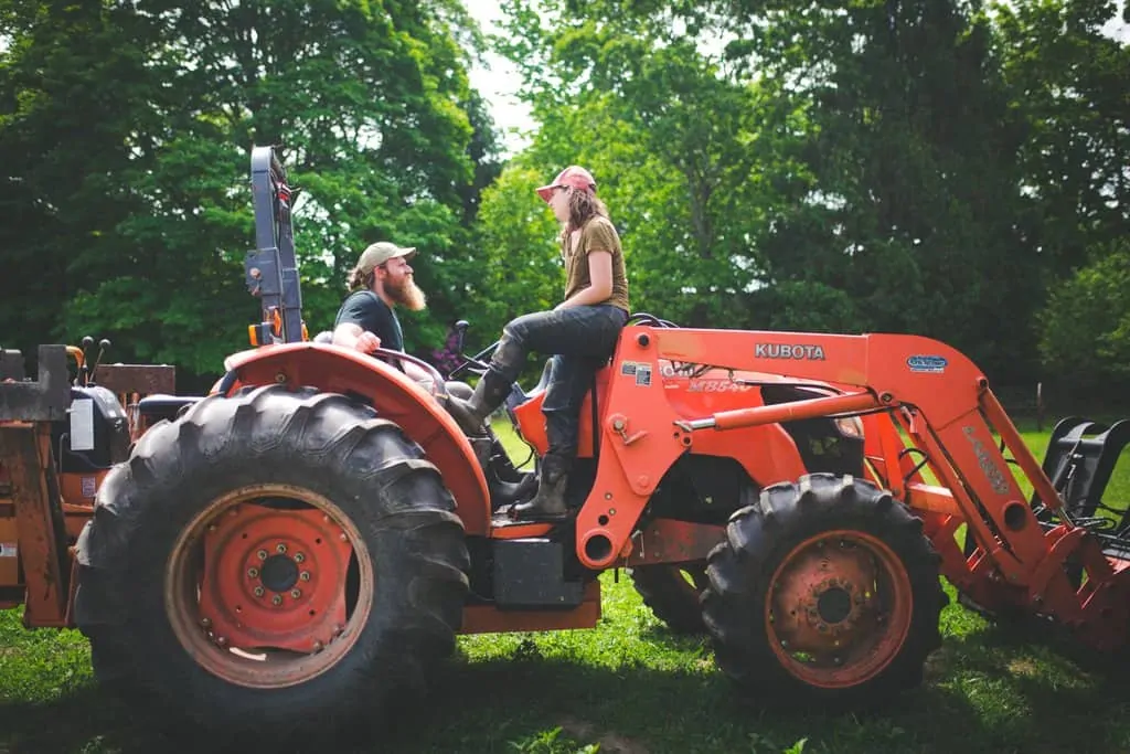 Farmers at Osamequin Farm on a Kubota utility tractor