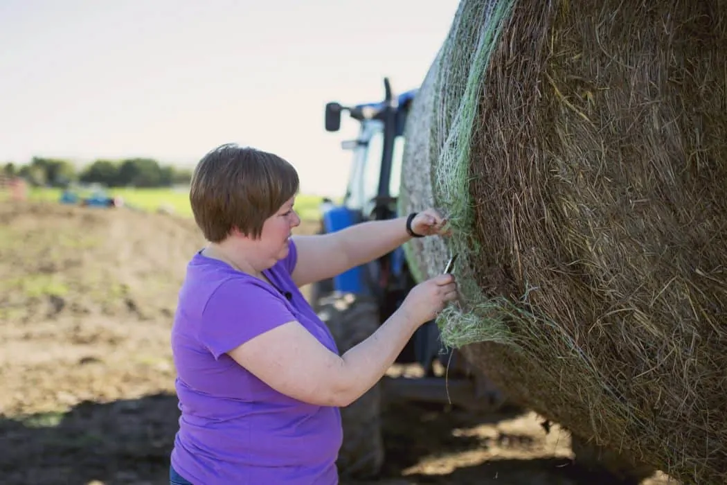FarmHer Erin Cumings works with her husband to unload a bale of hay for their herd of cattle on their Iowa farm.