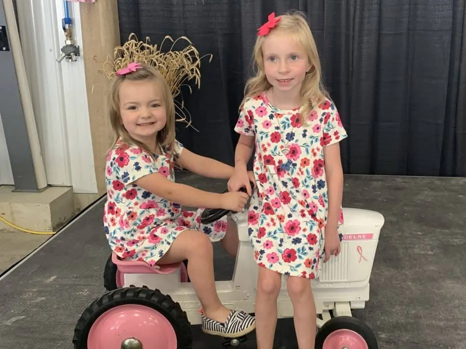 The Porteus grandaughters sit on a pink tractor at the cultivating a cure cancer fundraising event.