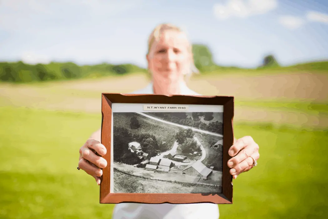 Sara Wyant holds an old photo of her family's farm in Iowa.