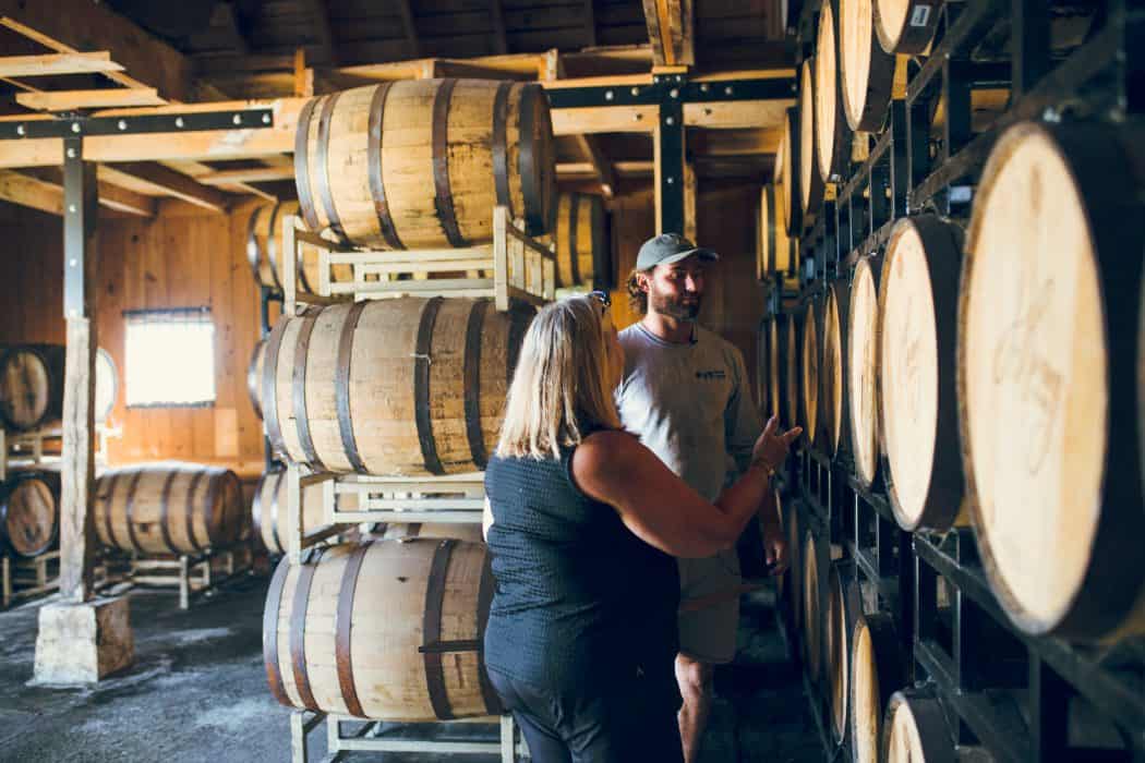 Liz and Joe Henry of J. Henry & Sons bourbon standing by barrels of bourbon.