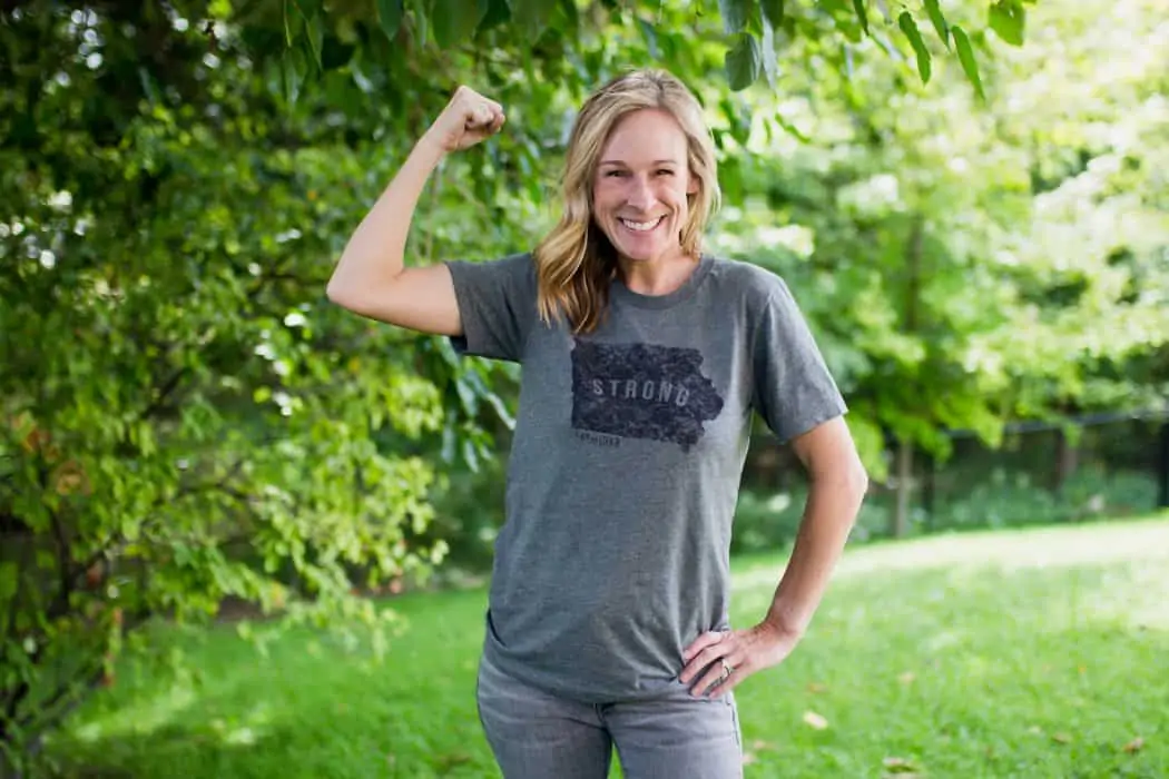 Marji Guyler-Alaniz wearing an Iowa Strong tee shirt flexing her muscles. 