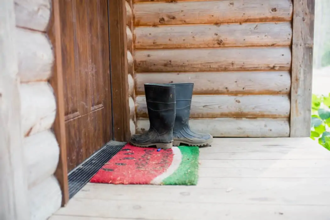 Work boots on a doorstep of a farm with a watermelon rug.