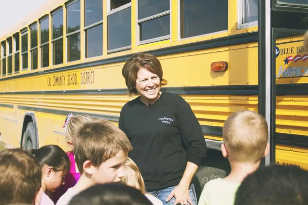 A school bus load of children greeted by woman at Enchanted Acres.