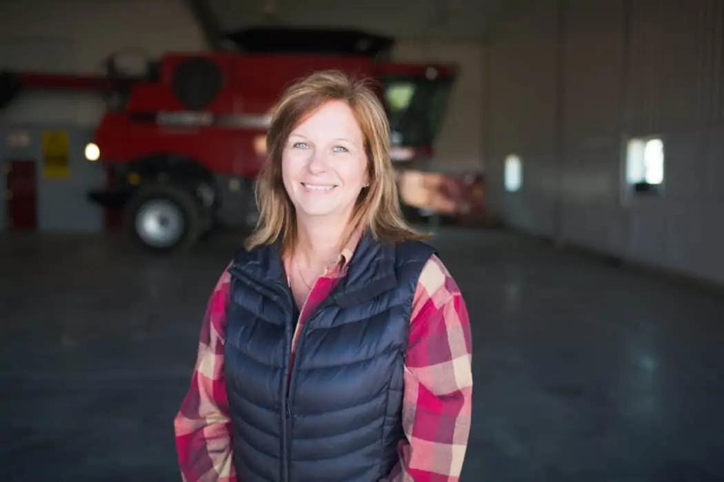 Jolene Palmer in a shop on her farm with a Case IH combine behind her.