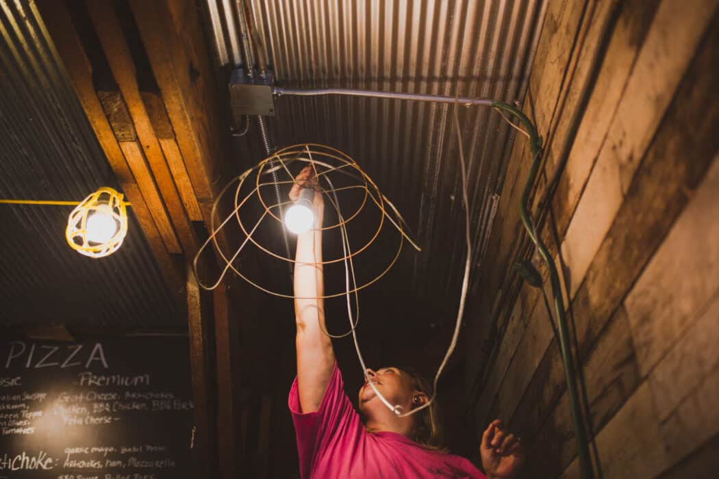 Woman replacing light bulb in a barn on a farm.