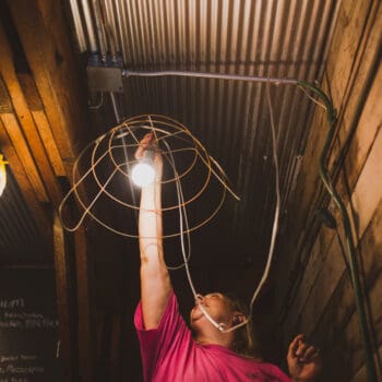 Woman replacing light bulb in a barn on a farm.