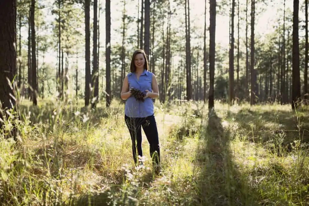 A woman standing on land with trees.