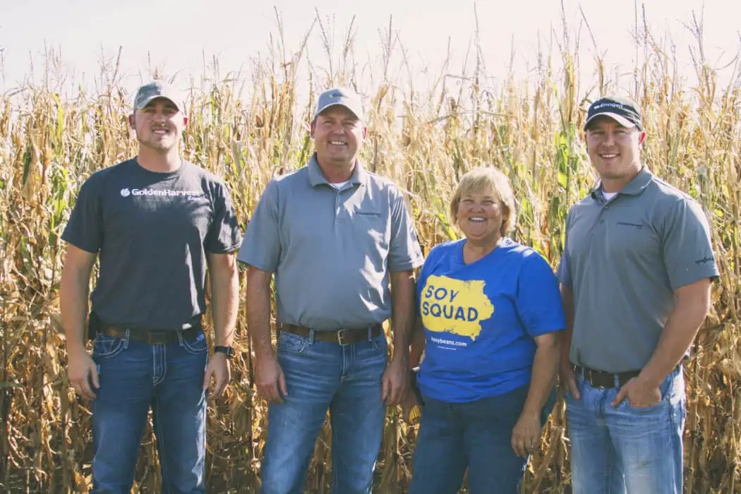 A woman standing in a corn field with three seed dealers