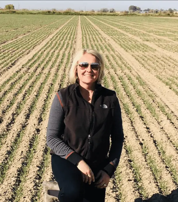 Shannon Hauf with Bayer Crop Science kneeling in a field