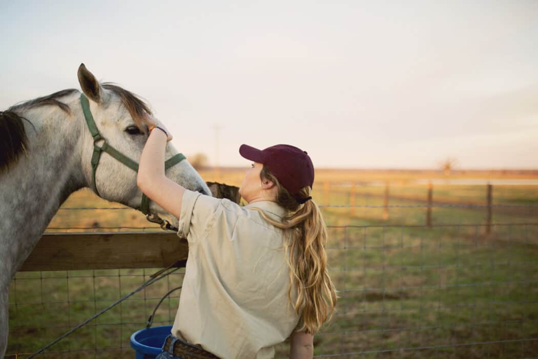 Woman rancher petting horse in a pasture