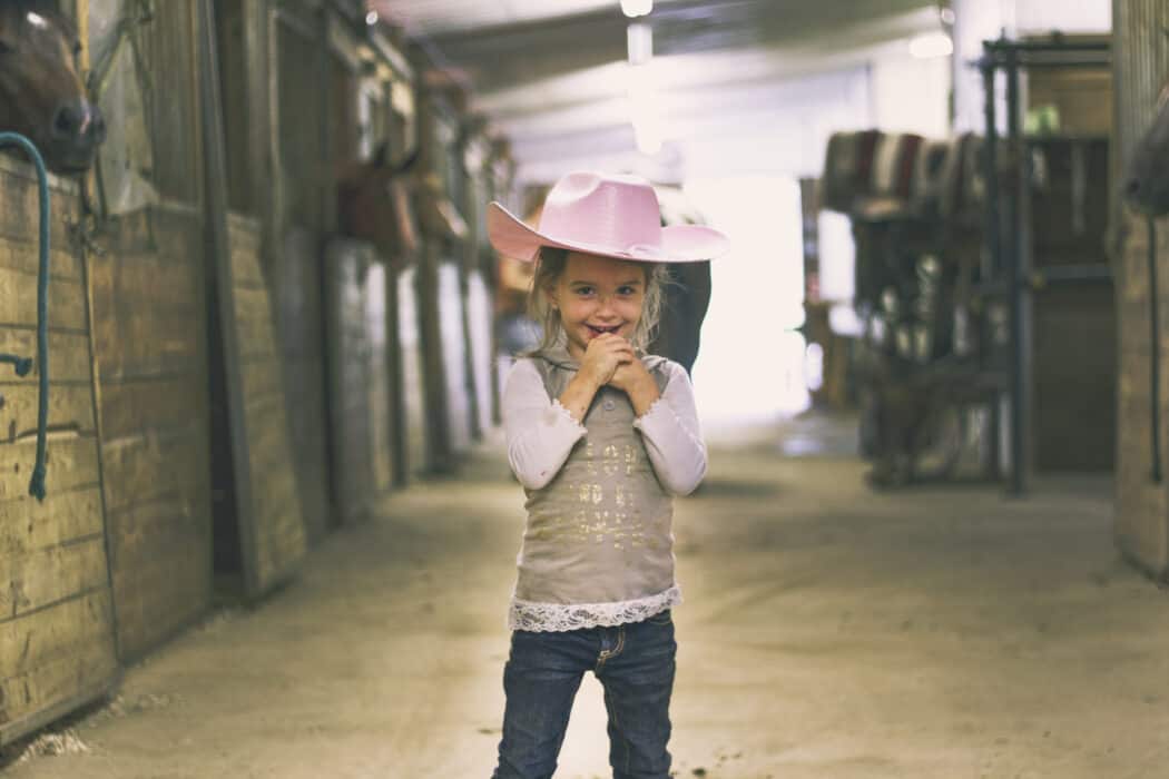 Young girl with pink cowgirl hat on at a horse ranch