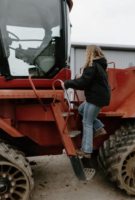 A woman getting into a red tractor on the farm