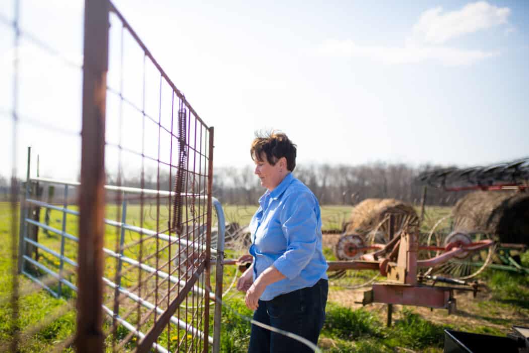 A woman working on the farm and shutting a gate