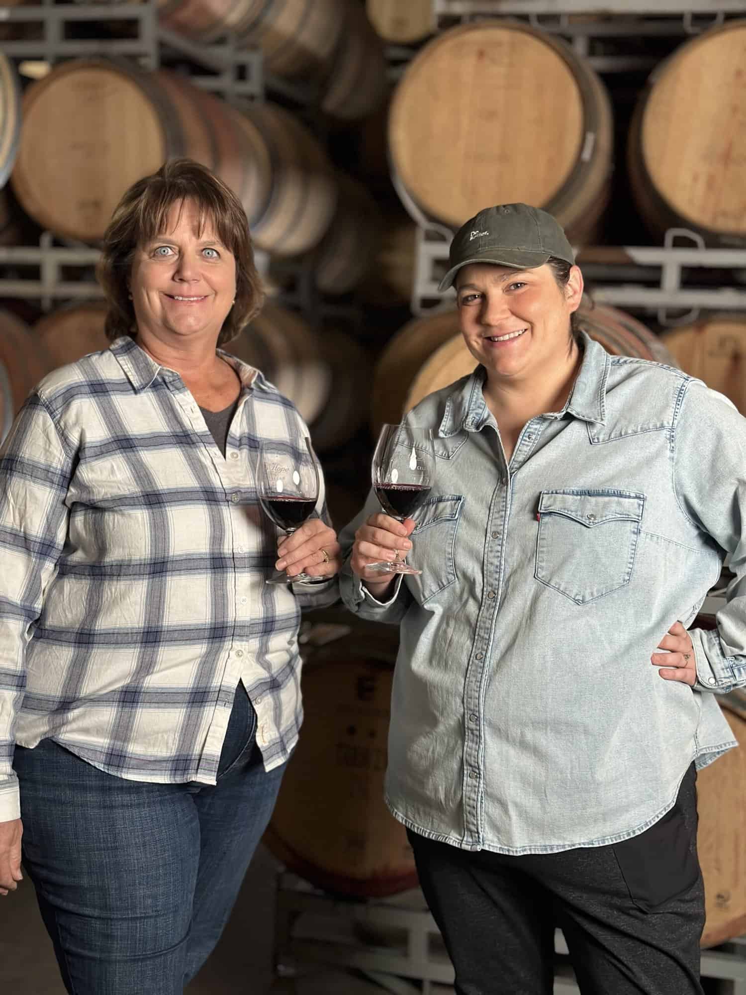Stasi Seay and Samantha Taylor of Hope Family Wines holding two glasses of red wine.